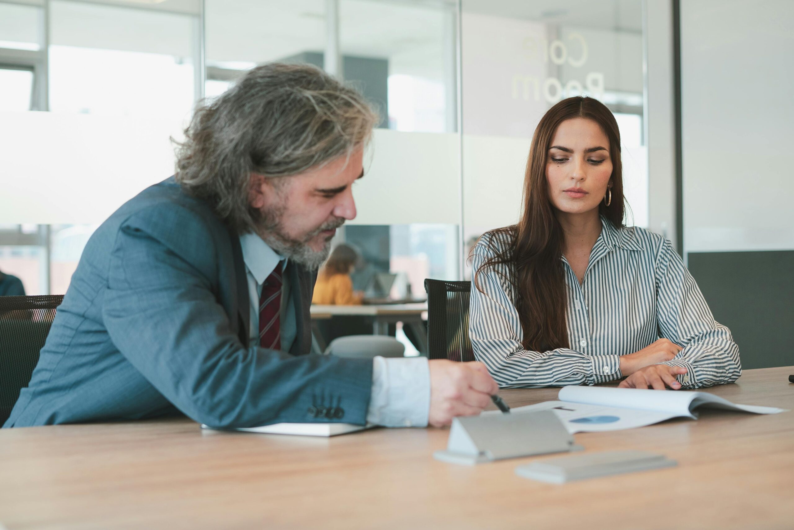 Professional meeting with two colleagues discussing documents at an office table.